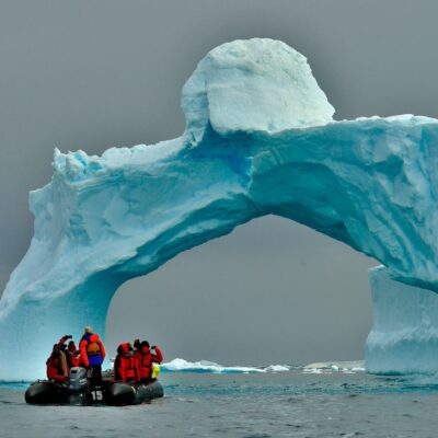 People sailing towards a big ice in Antarctica.
